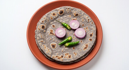 traditional Indian Gujarati food roasted flat bread bajra roti or bhakri with onion slice and chili pepper, jawar roti on earthen clay tawa pan, white background 