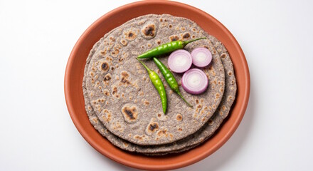 traditional Indian Gujarati food roasted flat bread bajra roti or bhakri with onion slice and chili pepper, jawar roti on earthen clay tawa pan, white background 