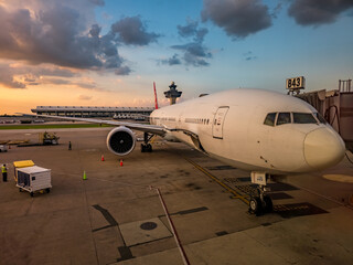 White airplane at the gate at IAD Washington airport waiting to be unloaded with sunset sky