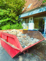 Construction Waste Management A large red dumpster overflowing with debris at a busy site...