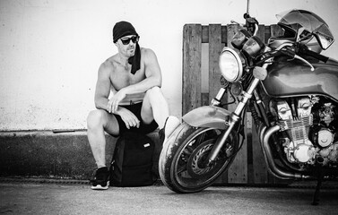 Man Resting by Vintage Motorcycle on a Hot Summer Day Black and White Urban Scene