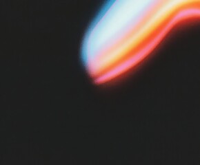 Colorful smooth gradient with noise texture spreading across a dark background. Abstract futuristic light art.