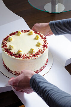 Manos empacando una torta o pastel Red Velvet en caja para env&iacute;o y entrega a cliente. 
