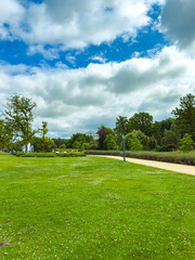 Immerse yourself in a tranquil park landscape, where the lush green grass meets a beautifully cloudy sky, creating a serene atmosphere perfect for relaxation and outdoor activities