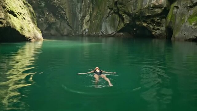 Attractive woman swimming on vacation in emerald water of in Mexico cenote close to Riviera Maya. Cancun and Playa Del Carmen nature attractions