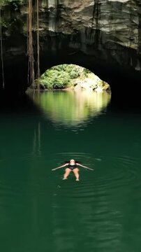 Attractive woman swimming on vacation in emerald water of in Mexico cenote close to Riviera Maya. Cancun and Playa Del Carmen nature attractions