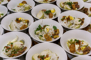 Bowls of soto, a traditional Indonesian dish with rice cake, vermicelli, and egg. Served for a...