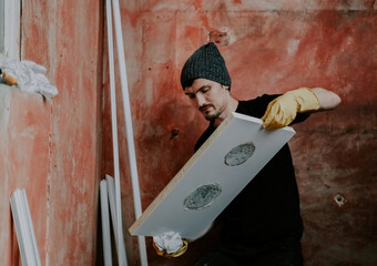 A man washes a plastic part of a window frame.