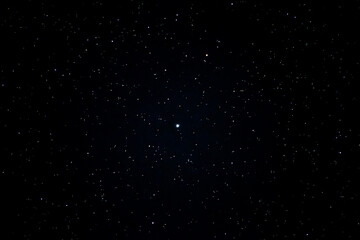 Bright star centered in clear night sky with stars scattered in darkness