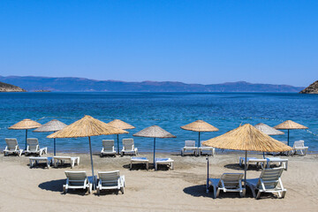 Empty beach with straw umbrellas and loungers