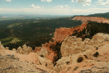 Layered rock formations, hoodoos, red cliffs at bryce canyon national park utah with blue skies and puffy clouds and trees