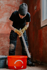 A guy washes the plastic part of the frame with a sponge in a bucket.