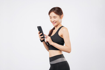 Holding phone and tapping phone screen, this sporty woman smiles in gym gear, embracing fitness,...