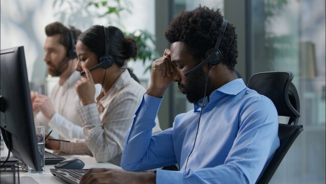 Frustrated multiethnic operators callcenter business crisis computer headache Caucasian African men depressed sad agent headset failure service bad call center Hispanic woman helpline support office