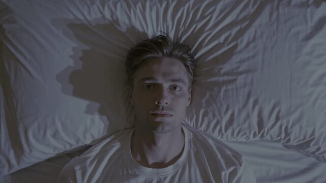 Intense portrait. A man stares directly at the viewer, bathed in soft light against a textured white background