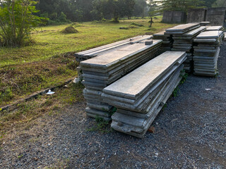 Pile of left over thin long concrete masonry block slabs, on the road side