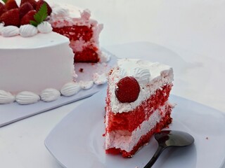 Delicious Strawberry Cake Slice with Creamy Frosting and Fresh Berries on a White Plate.