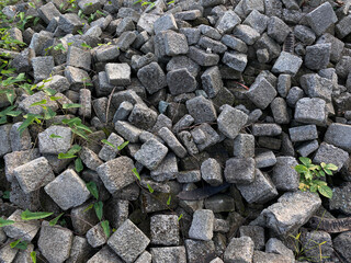 Pile of left over pavers, flooring or concrete block paving, cube shape, with green vines
