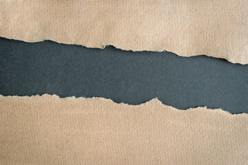 Brown cardboard ripped paper torn edges on dark gray background.