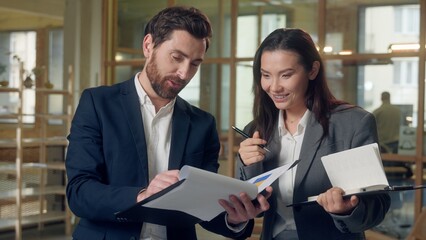 Multiethnic business team Korean excited businesswoman presenting colorful chart folder happy Caucasian businessman teamwork discussion strategy leader partners office report planning clipboard ideas