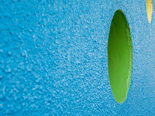 Blue rough walls with circular holes painted in green and yellow