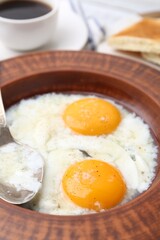 Half-boiled eggs in plate and spoon on table, closeup. Traditional asian breakfast