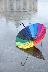 One colorful umbrella on wet asphalt outdoors