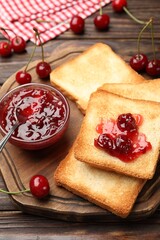 Toasts with tasty cherry jam and fresh fruits on wooden table, closeup