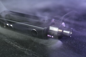 Modern electronic smoking device on black table, closeup