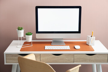 Stylish workplace with computer and orange mousepad on white table indoors. Space for text