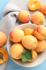 Fresh apricots with green leaves on light blue wooden table, flat lay