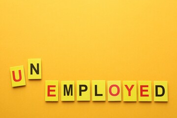 Word Unemployed on yellow background, top view. Space for text