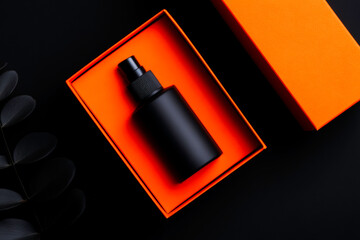 Black cosmetic bottle in orange box on dark background beauty product