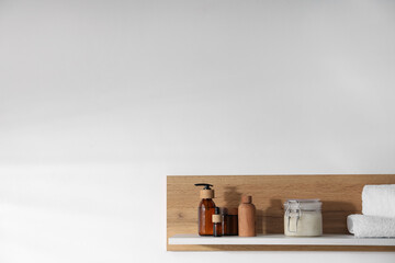 Wooden shelf with cosmetic products and towels on white background. Space for text