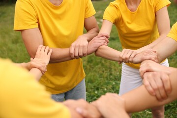 Team building. Group of people joining hands outdoors, closeup