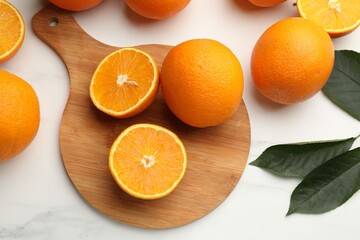 Fresh oranges and leaves on white table, flat lay