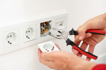 Man fixing power sockets with pliers indoors, closeup