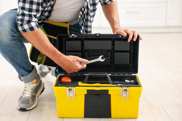 Man taking wrench from tool box indoors, closeup
