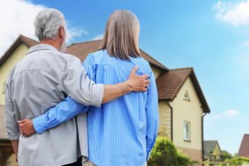 Senior couple looking at their house outdoors, back view