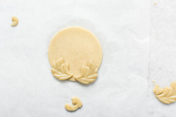 overhead view of vanilla sugar cookie dough being decorated on parchment lined tray, top view of plain cookie dough, process of making sugar cookies