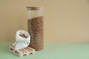 Refillable glass jar with raw buckwheat porridge and cotton bag. Copy space Refill product format...