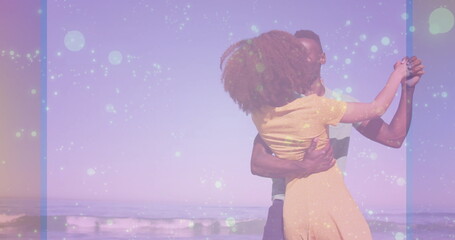 Dancing couple embracing on sandy beach under pastel sky, with gentle waves rolling