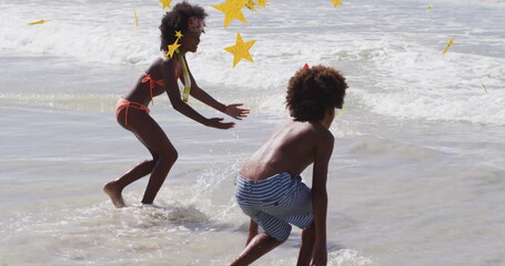 Splashing siblings diving in shallow ocean water at beach, with swim goggles and foamy waves