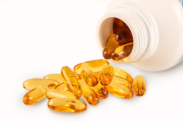 Cod liver oil capsules spilling out of bottle isolated on white background.