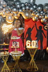 Woman celebrating 60th birthday party with themed decorations and cake
