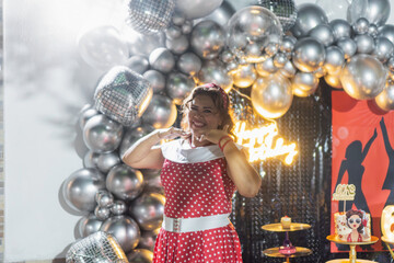 Enthusiastic woman making telephone gesture at 60s themed birthday party