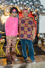 Father and son wearing 70s themed clothes posing at birthday party