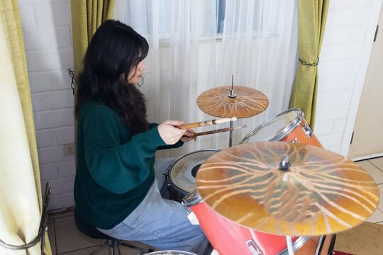 latina Woman practicing acoustic drums at home