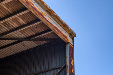 Rusty industrial warehouse roof against clear sky. Detailed view of a rusty warehouse roof...