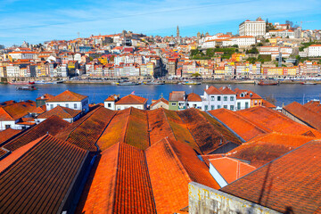 Terracotta rooftops stretch toward the Douro River, with colorful hillside buildings of Porto...